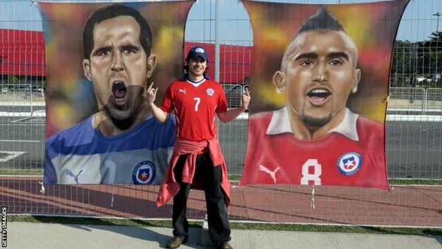 A Chile fans poses with posters of goalkeeper Claudio Bravo, left, and midfielder Arturo Vidal outside Arena de Sao Paulo