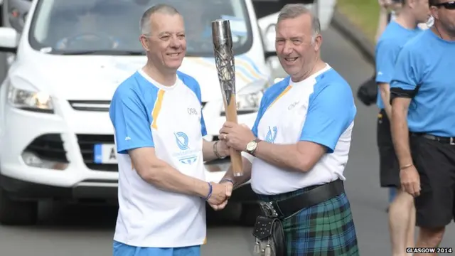 Two baton bearers shake hands as they pass baton.