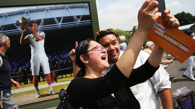 Fans take a selfie in front of a picture of Andy Murray