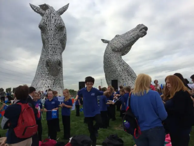 People stand in front of Kelpies statues