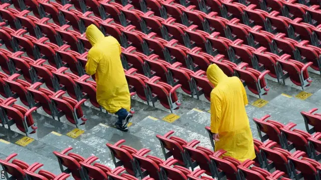 Stewards attempt to clear the stands of water