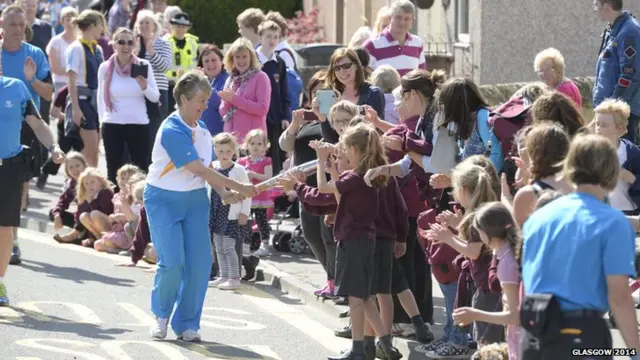 Georgina Logan stops with baton to allow the crowds to get a chance to hold it.