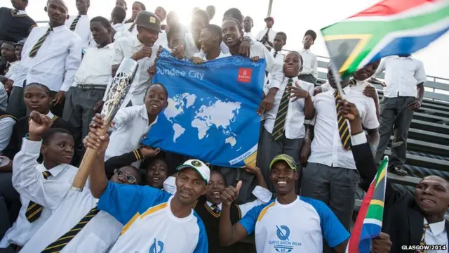 South African school children pose with Queen's baton and a banner saying 'Dundee City'.