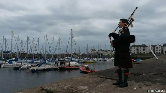 Piper plays at a harbour full of boats