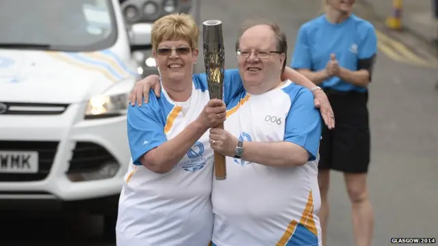 Anne Garrick and David Mills pose with Queen's baton