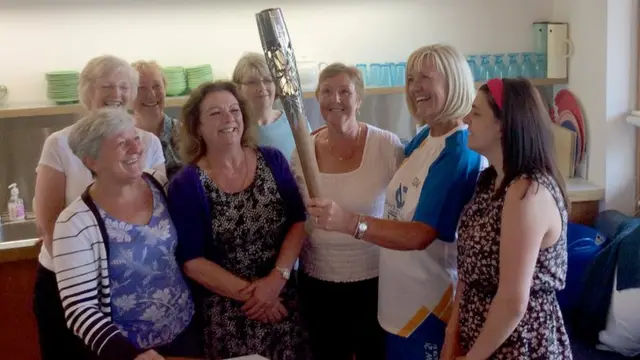 Group of ladies admire Queen's baton