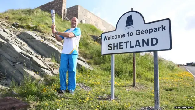 Darren Hall carries the Glasgow 2014 Queen's Baton through Sumburgh on the Shetland Islands.