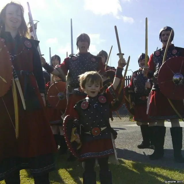 Group of people dressed as Vikings, with small boy front and centre holding sword aloft.