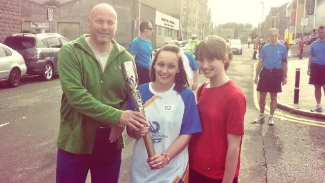 Batonbearer flanked by woman and totally bald middle-aged man