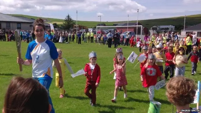 Claire Johnston carries baton followed by group of children