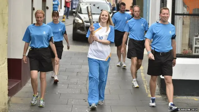 Vicki Smith carries baton flanked by police escort