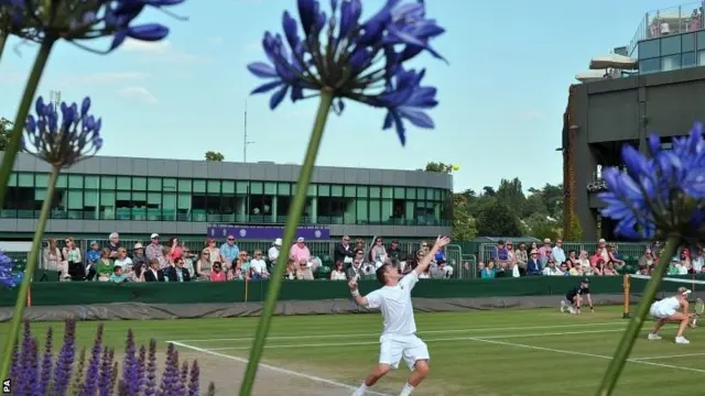 Great Britain's Neal Skupski and Naomi Broady are seen through the flowers in their Mixed Doubles match