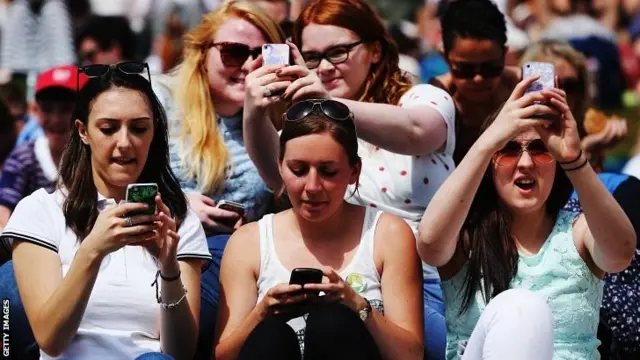 Spectators on their phones on Henman Hill