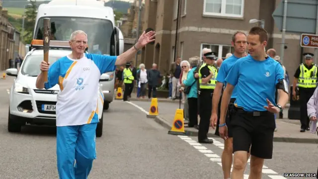 James Green waves as he carries baton.