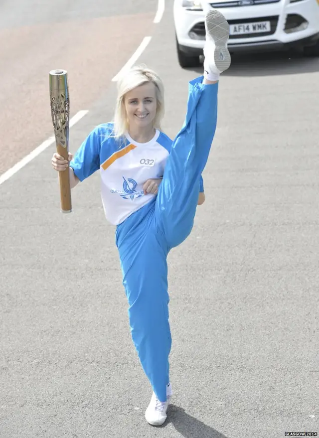 Kimberley Clarke holds baton while extending one leg up past her head