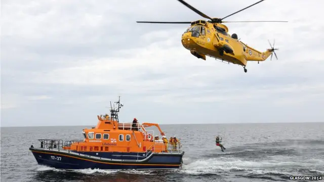 Helicopter winches man carrying Queen's baton onto lifeboat