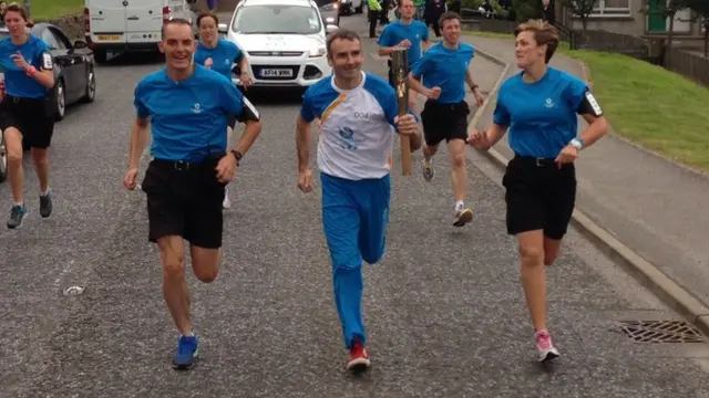 Neal Anderson running with Queen's baton.