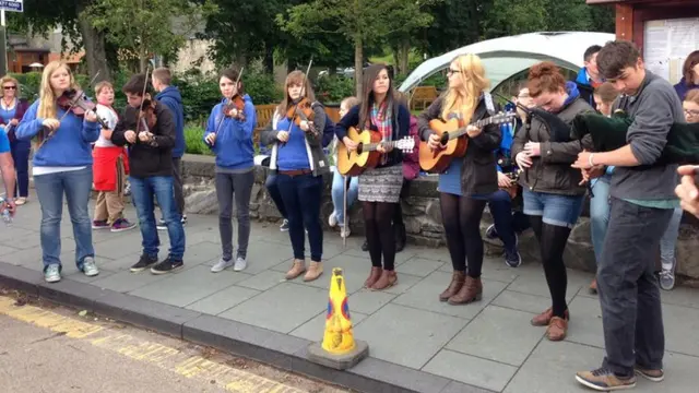 Traditional Irish band perform at roadside behind a traffic cone.