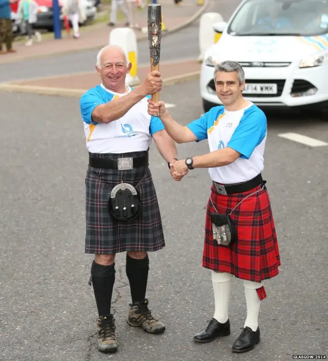 Rex Sircus and Michael Dixon both hold baton, and both are in kilts