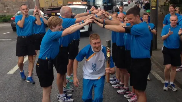 Kenny Wilson passes under archway of arms while holding baton