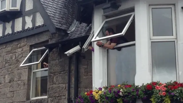 Spectators watch baton relay hanging out of windows