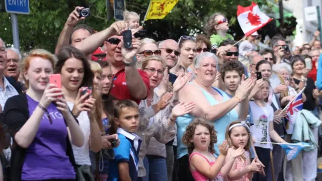 Large crowd taking pictures and waving flags