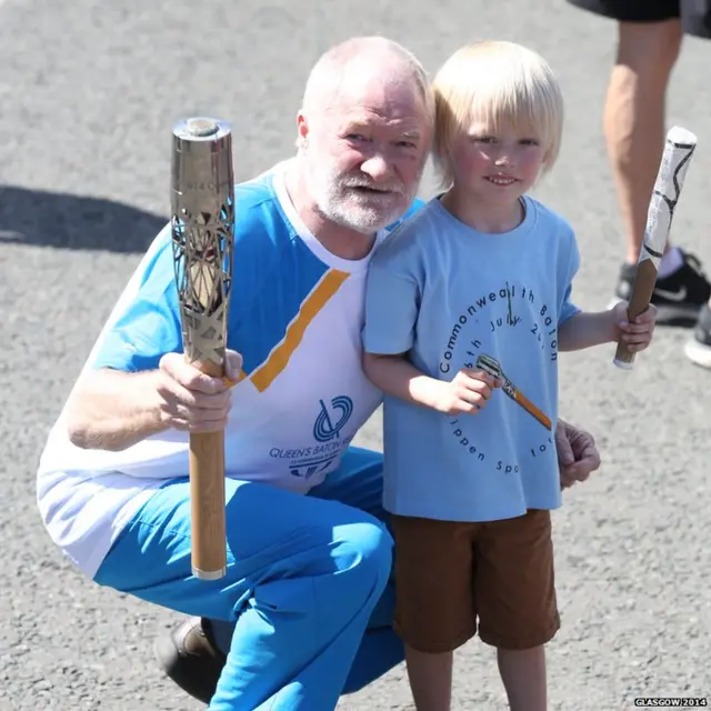 Sandy Kelso poses with Queen's baton and small boy.