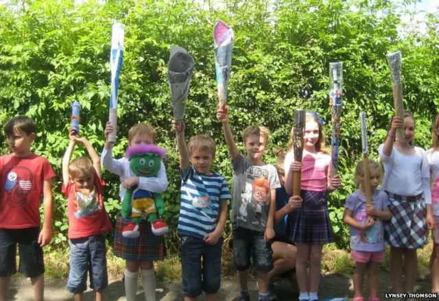 Line of children all holding replica Queen's batons.