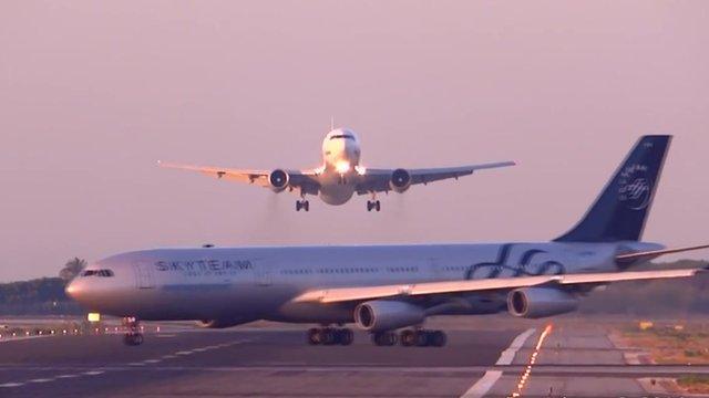 An Airbus 340 is shown crossing the runway at El Prat Airport as a flight from Moscow is coming in to land