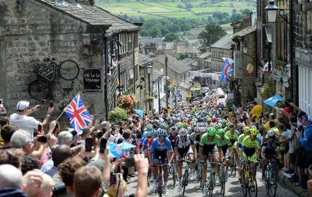 The peloton rides up Main Street as stage two of the Tour de France passes through Haworth, Yorkshire