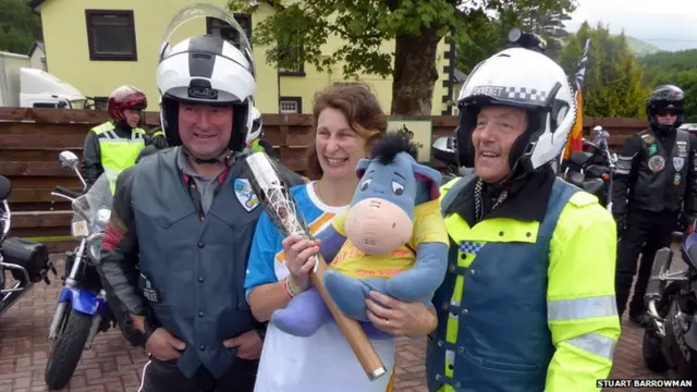 Baton bearer Diane Mailer poses with bikers and a stuffed 'Eeyore' toy