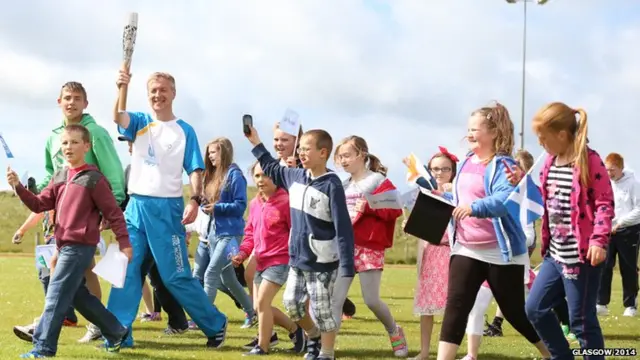 Iain MacDonald carries the Glasgow 2014 Queen's Baton at Linaclate School/Sgoil Lionacleit