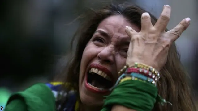 A Brazilian soccer fan cries as she watches her team