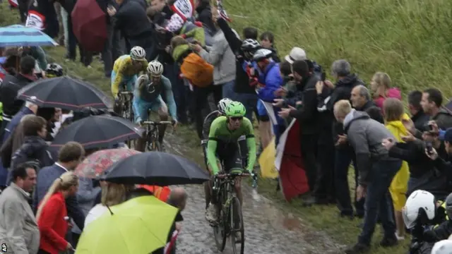 Italys Vincenzo Nibali, left, wearing the overall leaders yellow jersey, rides on a cobblestone-paved section of road in Ennevelin, northern France