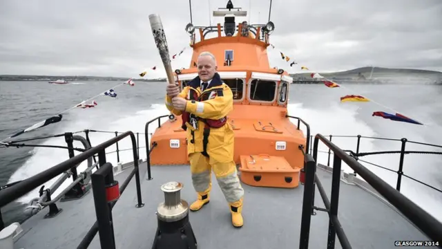 Graham Campbell carries the Glasgow 2014 Queen's Baton on an RNLI lifeboat from Hatston Harbour to Kirkwall Harbour