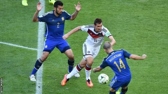 Miroslav Klose takes on Javier Mascherano