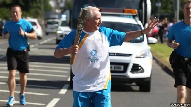 Ronald Cheyne waves to the crowds as the baton travels through Irvine in North Ayrshire.