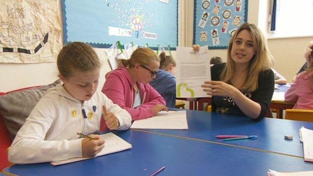 Reporter holding letter in classroom with pupils