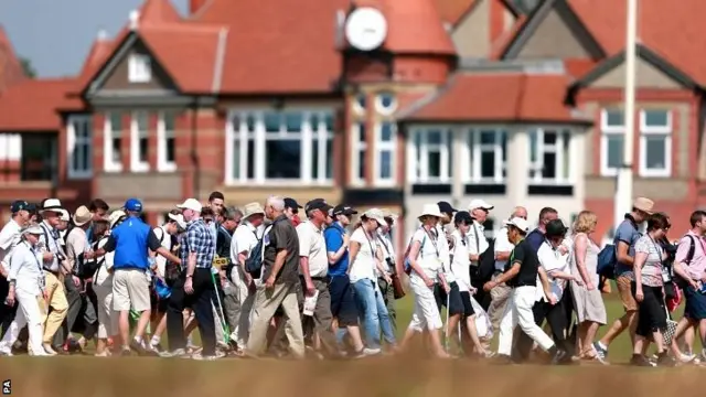 Crowds cross the course in front of the clubhouse