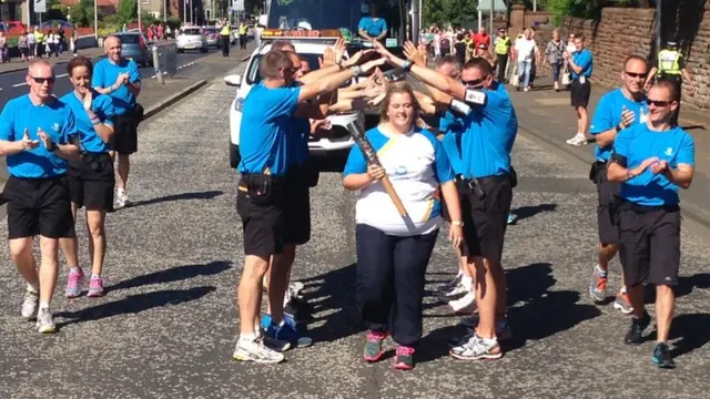 Baton bearer passes through archway of arms