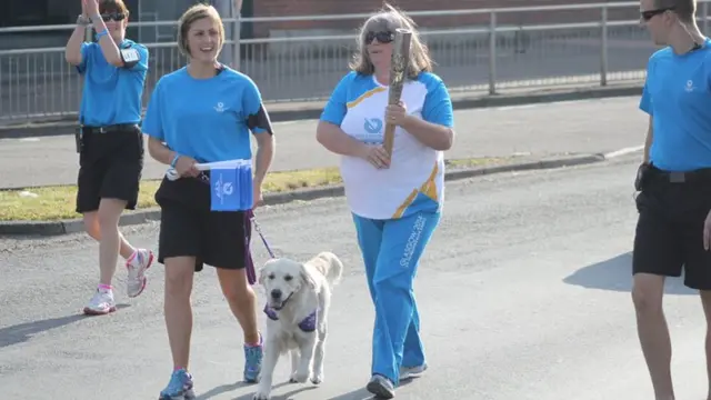 Baton bearer Lorraine Bonnar. One of the police escorts is leading an assistance dog.