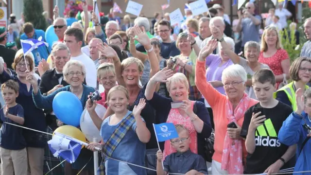 Large crowd of waving, smiling spectators.