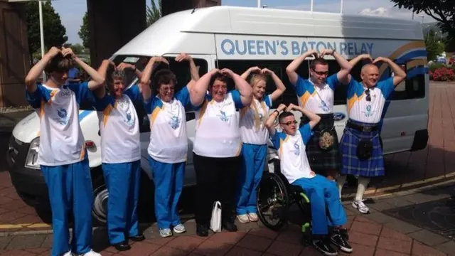 Baton bearers with hands on their heads so that their arms look like a letter 'm'