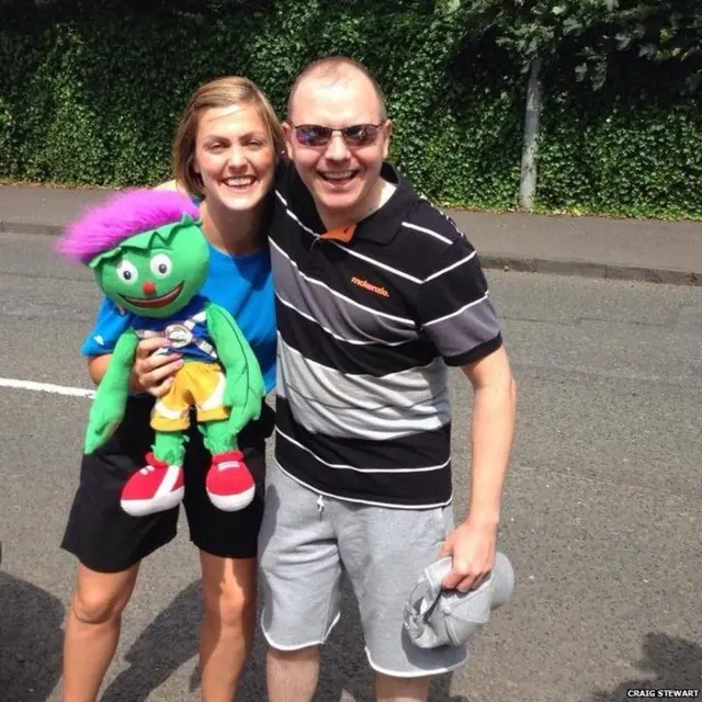 Craig Stewart poses with police escort who is holding a cuddly Clyde mascot