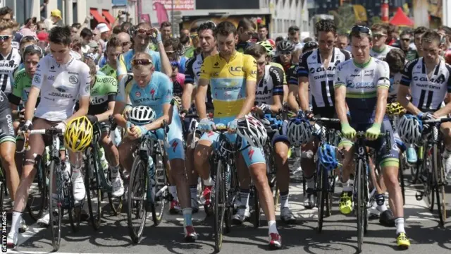 Riders observe a one minute silence before the start of stage 13