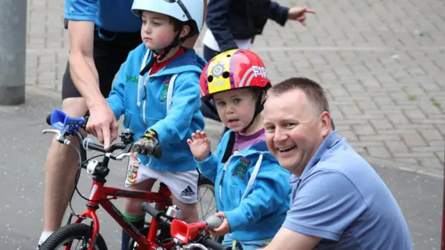 Small boy in replica firefighter's helmet waves