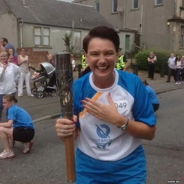 A smiling Karen Kelly holds Queen's baton