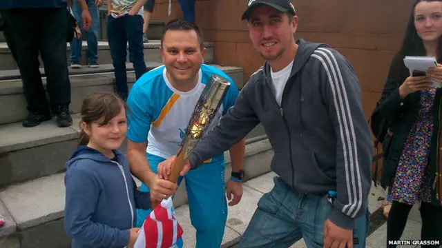 Baton bearer poses with man and young girl