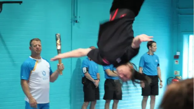 Baton bearer watches girl do somersault