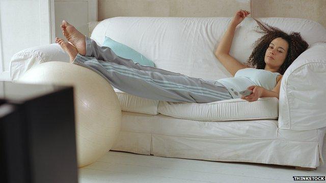Woman lying on sofa watching TV